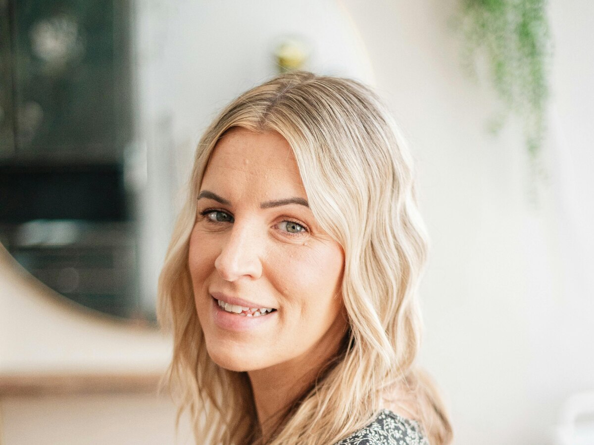 Blonde woman smiling while seated in a bright salon
